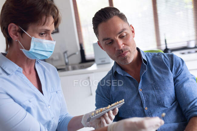 Enfermera dental caucásica examinando dientes con paciente masculino en clínica dental moderna. negocio de salud y odontología. - foto de stock