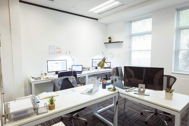 Interior de escritório moderno vazio com mesas, cadeiras, laptops e computadores. empresa e escritório local de trabalho. — Fotografia de Stock