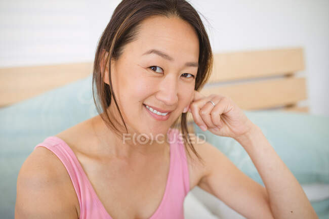 Retrato de una mujer asiática feliz sentada en la cama por la mañana. estilo de vida, pasar tiempo y relajarse en casa. - foto de stock