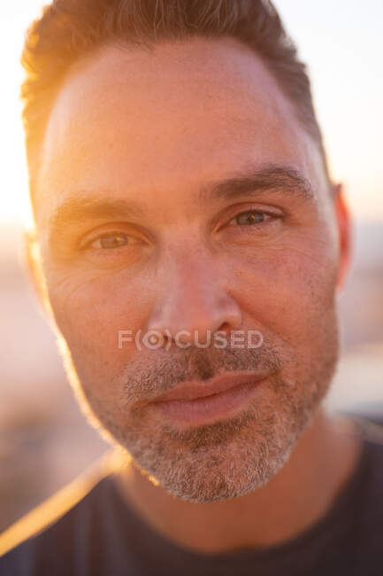 Portrait of thoughtful caucasian man looking at camera at seaside. summer road trip and holiday in nature. — Stock Photo