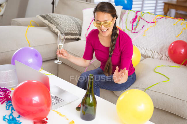 Feliz mulher asiática levantando taça de champanhe fazendo véspera de ano novo laptop chamada de vídeo. celebrar em casa com tecnologia de comunicação. — Fotografia de Stock