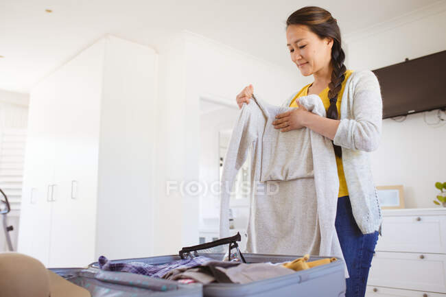 Happy asian woman preparing clothes and suitcase for travel. travel preparation during covid 19 pandemic. — Stock Photo