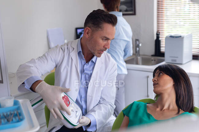 Dentista masculino caucasiano sorridente examinando dentes de paciente do sexo feminino na clínica odontológica moderna. serviços de saúde e odontologia. — Fotografia de Stock