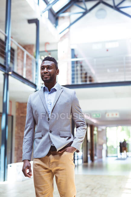 African american smiling businessman walking in modern office with colleagues in background. business and office workplace. — Stock Photo