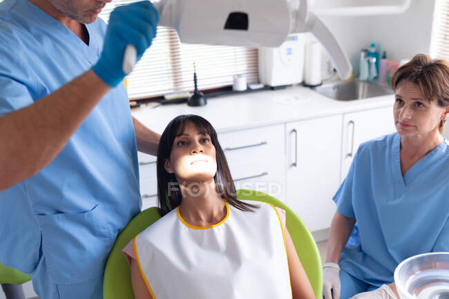 Dentista masculino caucasiano e enfermeira dentária feminina examinando os dentes do paciente na clínica odontológica moderna. serviços de saúde e odontologia. — Fotografia de Stock