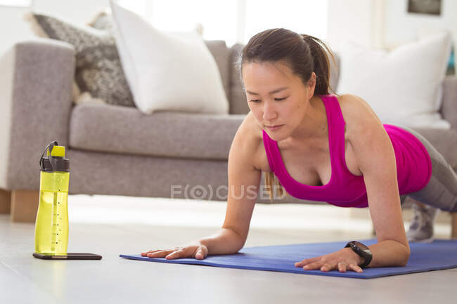 Focalizzato asiatico donna execrising su mat a casa. sano stile di vita attivo e fitness a casa. — Foto stock