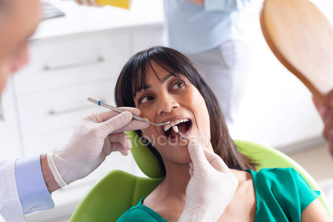 Caucasian male dentist examining teeth of female patient at modern dental clinic. healthcare and dentistry business. — Stock Photo