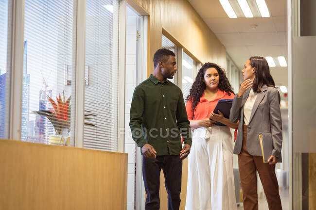 Groupe diversifié de gens d'affaires marchant, discutant du travail dans le bureau moderne. lieu de travail professionnel et de bureau. — Photo de stock