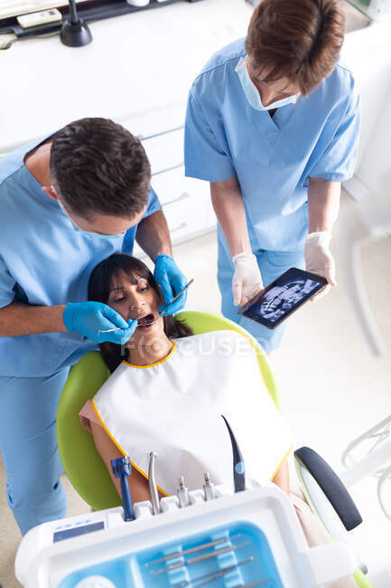 Кавказький самець-стоматолог і жінка-стоматолог, які вивчають зуби пацієнта в сучасній стоматологічній клініці. Медичне обслуговування та стоматологія. — стокове фото