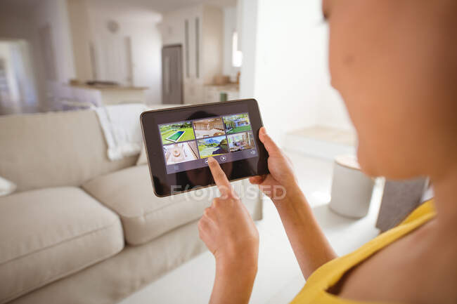 Asian woman using tablet with view from security cameras at home. security, safety, surveillance, and digital interface. — Stock Photo