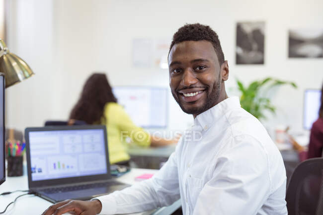 Retrato do sorridente empresário afro-americano olhando para a câmera no escritório moderno. empresa e escritório local de trabalho. — Fotografia de Stock