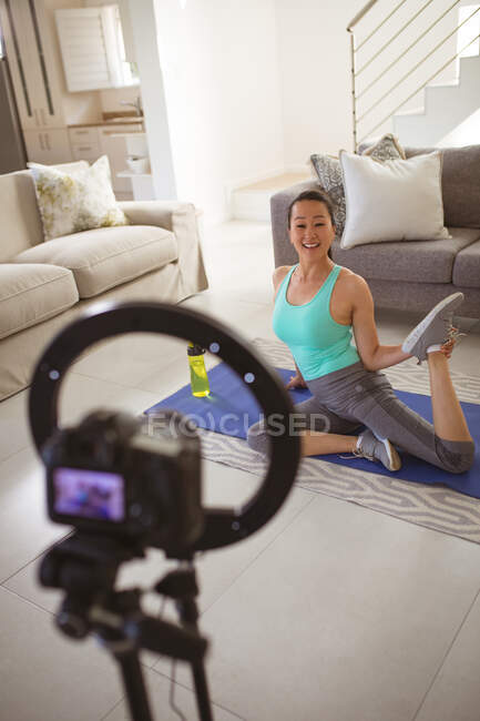 Glückliche asiatische Frau turnt auf Matte und macht fittnes vlog von zu Hause aus. gesunder aktiver Lebensstil und Fitness zu Hause mit Technologie. — Stockfoto