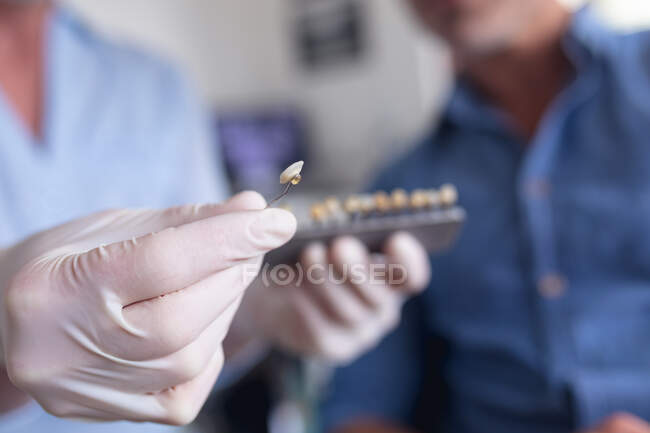 Dentista femenino sosteniendo y examinando los dientes con el paciente masculino en la clínica dental moderna. negocio de salud y odontología. - foto de stock