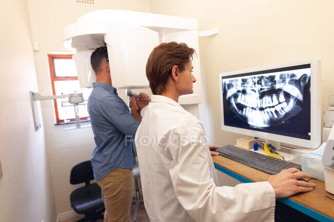Dentiste caucasienne examinant les dents du patient masculin à la clinique dentaire moderne. soins de santé et de la dentisterie. — Photo de stock