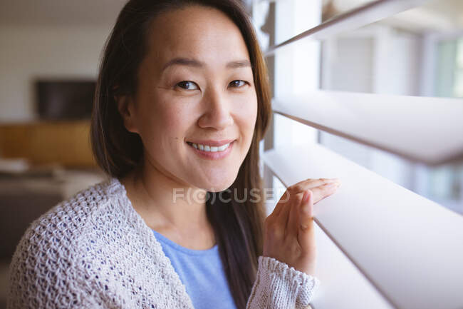 Retrato de mulher asiática feliz em pé na janela, olhando para fora. estilo de vida, lazer e passar o tempo em casa. — Fotografia de Stock
