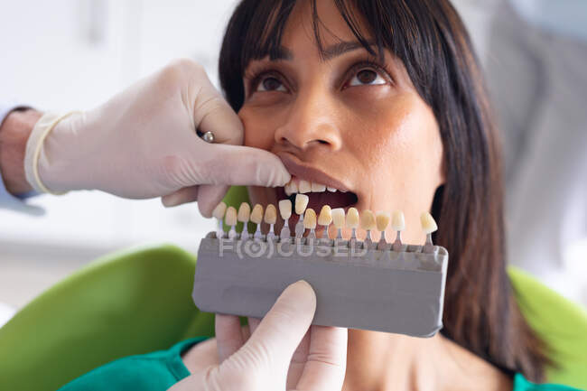 Кавказький самець-стоматолог вивчає зуби пацієнтки в сучасній стоматологічній клініці. Медичне обслуговування та стоматологія. — стокове фото