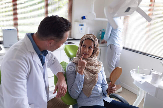 Kaukasischer Zahnarzt im Gespräch und bei der Untersuchung der Zähne einer Patientin in einer modernen Zahnklinik. Gesundheits- und Zahnarztgeschäft. — Stockfoto