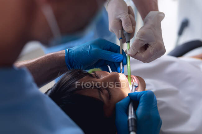 Кавказский врач-стоматолог и женщина-медсестра, осматривающая зубы пациента в современной стоматологической клинике. здравоохранение и стоматология. — стоковое фото