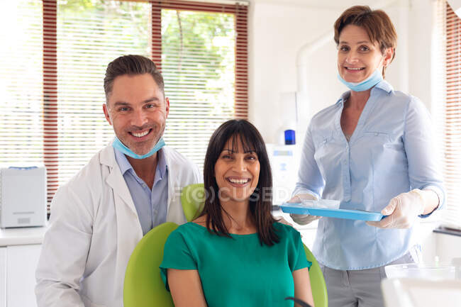 Retrato de sonriente dentista diverso, enfermera dental y paciente en la clínica dental moderna. negocio de salud y odontología. - foto de stock
