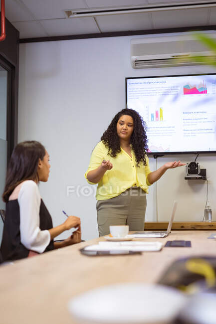 Zwei unterschiedliche Geschäftsfrauen sitzen am Tisch und diskutieren beim Treffen im modernen Büro. Geschäfts- und Büroarbeitsplätze. — Stockfoto