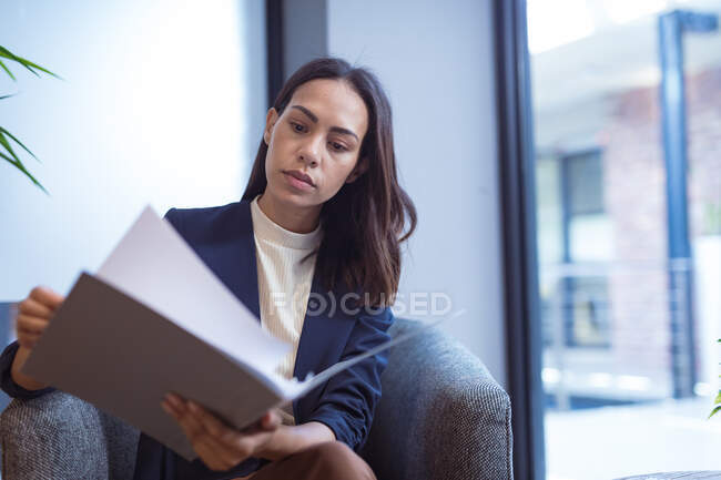 Бізнес-леді перевіряє документи з колегами на задньому плані в сучасному офісі. на роботі та в офісі. — стокове фото