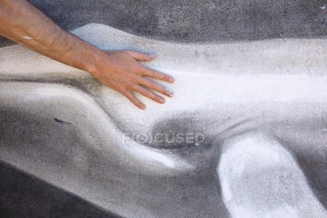 Обрезанная рука художника мужского пола прикасалась к фреске кита на стене. стрит-арт и мастерство. — стоковое фото