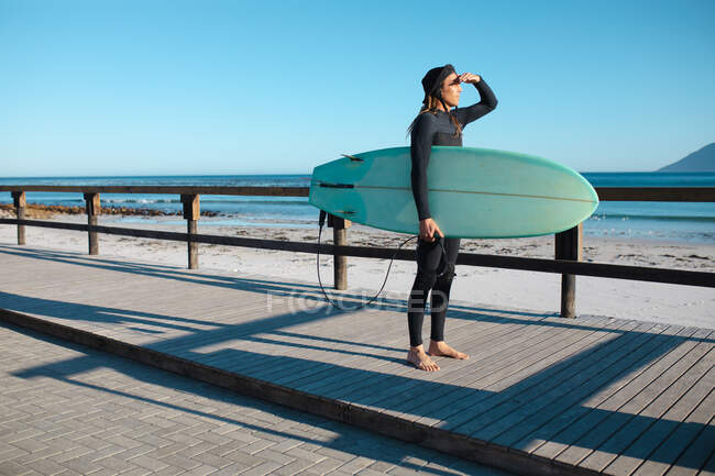Männlicher Surfer mit Surfbrettaugen, während er am Strand auf dem Dielenbrett steht. Hobbys und Wassersport. — Stockfoto