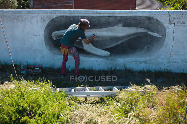 Visão traseira do pintor masculino fazendo bela pintura mural de baleia na parede. arte de rua e habilidade. — Fotografia de Stock