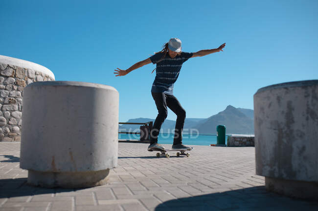 Männer skateboarden in voller Länge an Betonpollern auf der Promenade vor strahlend blauem Himmel. Lifestyle und Sport. — Stockfoto