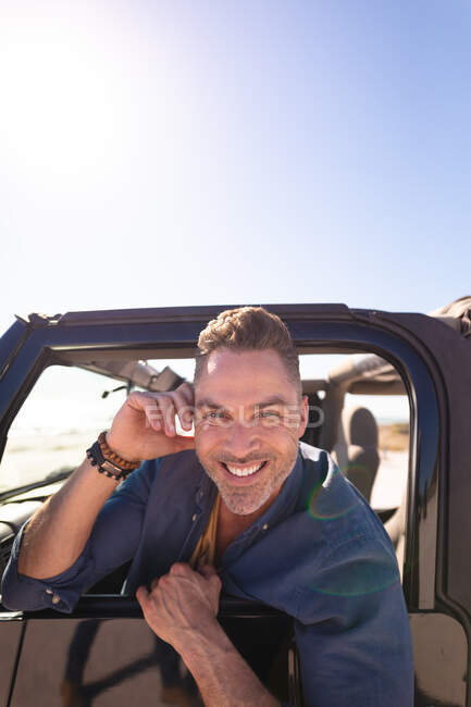 Портрет щасливого, усміхненого кавказького чоловіка, що сидить у машині на узбережжі. літня дорога поїздка і відпочинок на природі . — стокове фото