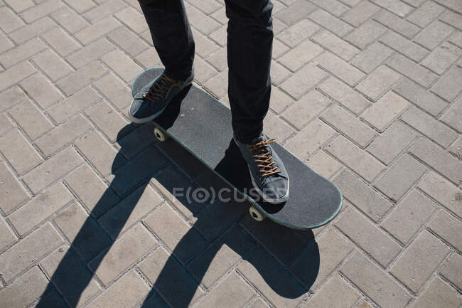 Section basse de l'homme équilibrage sur planche à roulettes à la promenade pendant la journée ensoleillée. mode de vie et sport. — Photo de stock