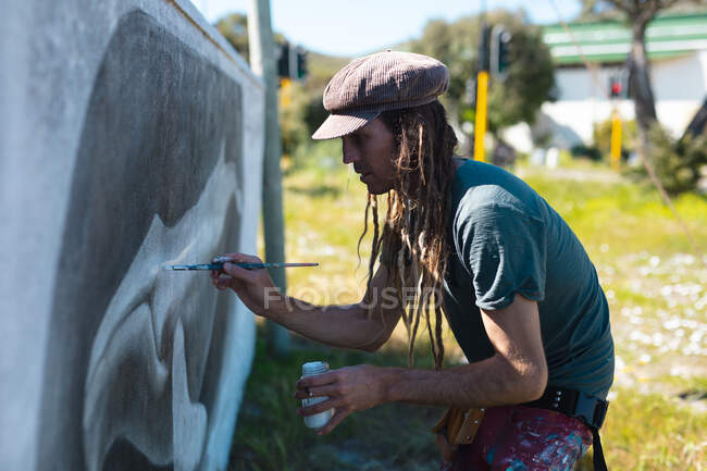Artista masculino se concentrando ao fazer pintura mural de baleia criativa na parede com pincel. arte de rua e habilidade. — Fotografia de Stock
