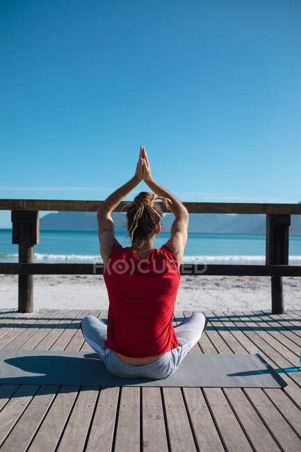 Rückansicht des Menschen, der Yoga praktiziert, während er meditiert, die Hände auf dem Dielenbrett zusammengeklammert, Kopierraum. Fitness und gesunder Lebensstil. — Stockfoto