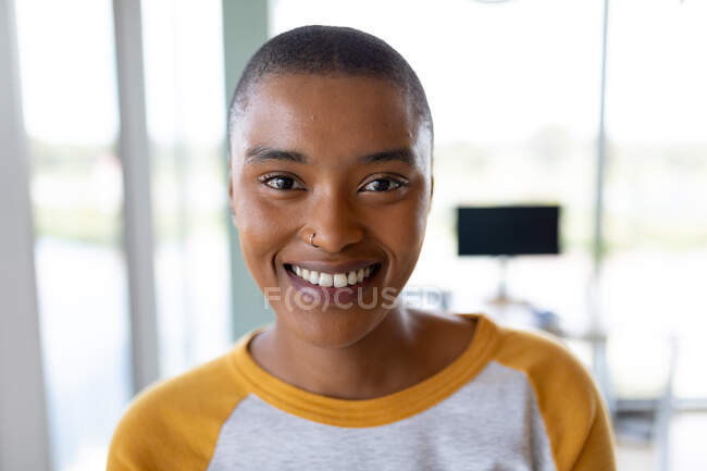 Retrato de sorridente empresária criativa afro-americana com cabelo curto no escritório. negócios criativos e local de trabalho de escritório. — Fotografia de Stock