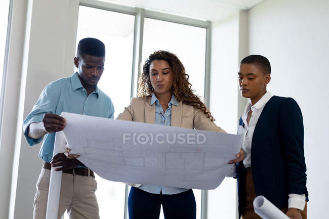 Biracial architect discussing with colleagues over blueprint in creative office. business, architect and creative office. — Stock Photo