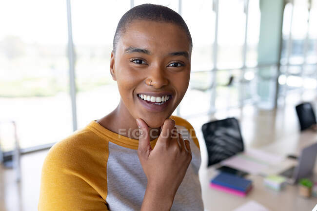 Portrait of smiling african american businesswoman with short hair in creative office. creative business and office workplace. — Stock Photo
