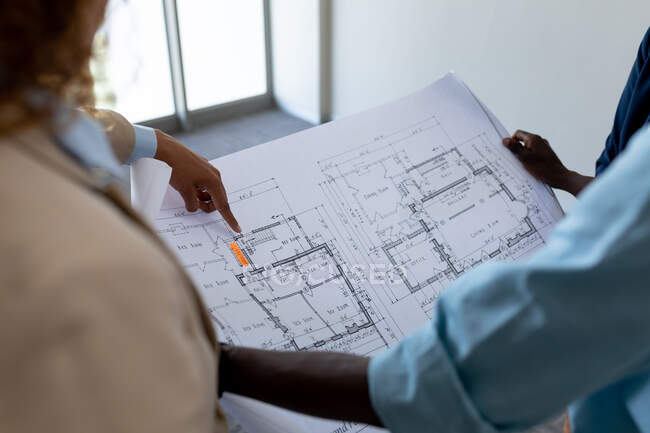 Female architect pointing at blueprint during meeting with colleagues in office. business, architect and creative office. — Stock Photo
