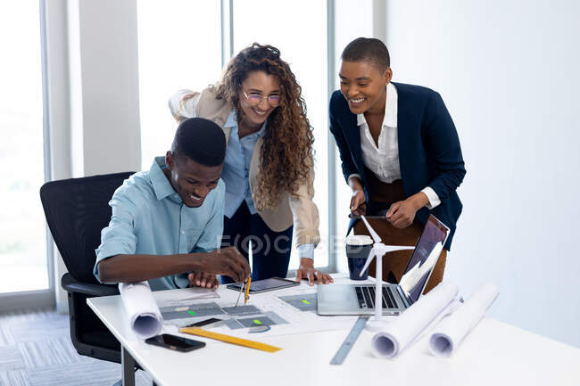 Smiling multiracial male and female architects working on blueprint in office. business, architect and creative office. — Stock Photo