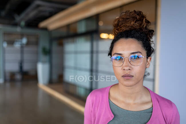 Retrato de empresária birracial confiante vestindo óculos no escritório criativo. negócios criativos e local de trabalho de escritório. — Fotografia de Stock