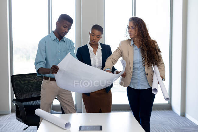 Arquitectos multiraciales masculinos y femeninos discutiendo sobre el plano en la oficina. negocio, arquitecto y oficina creativa. - foto de stock