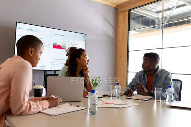 Коллеги-мультирасовые мужчины и женщины в повседневной жизни обсуждают бизнес-стратегию в зале заседаний. креативный бизнес, современные офисные и беспроводные технологии. — стоковое фото