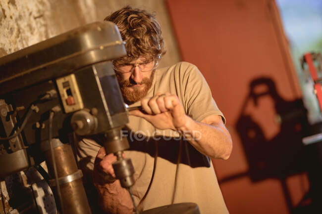 Kaukasischer Schmied mit Schutzbrille, während er an Maschinen in der Metallindustrie arbeitet. Schmiede-, Metall- und Fertigungsindustrie. — Stockfoto