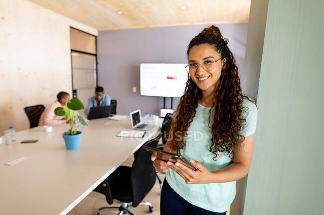 Portrait of confident biracial businesswoman in casuals using tablet pc in creative office. creative business, modern office and wireless technology. — Stock Photo