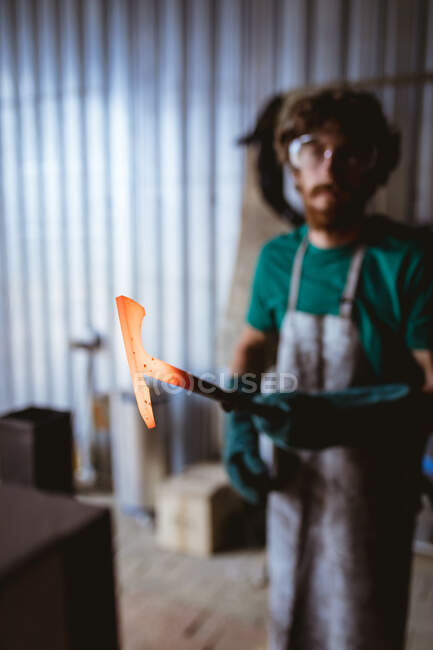 Ferreiro segurando metal em forma de martelo quente enquanto trabalhava na indústria de fabricação. indústria de forjamento, metalurgia e indústria transformadora. — Fotografia de Stock