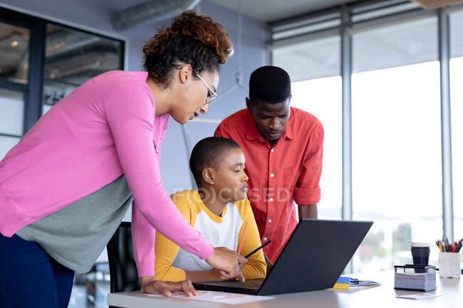 Multiracial male and female colleagues in casuals discussing over laptop in meeting at office. creative business, modern office and wireless technology. — Stock Photo