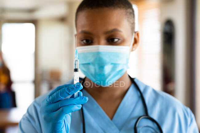 Женщина-врач в защитной маске смотрит на вакцину во время вспышки коронавируса. услуги здравоохранения, профилактики заболеваний и пандемии. — стоковое фото