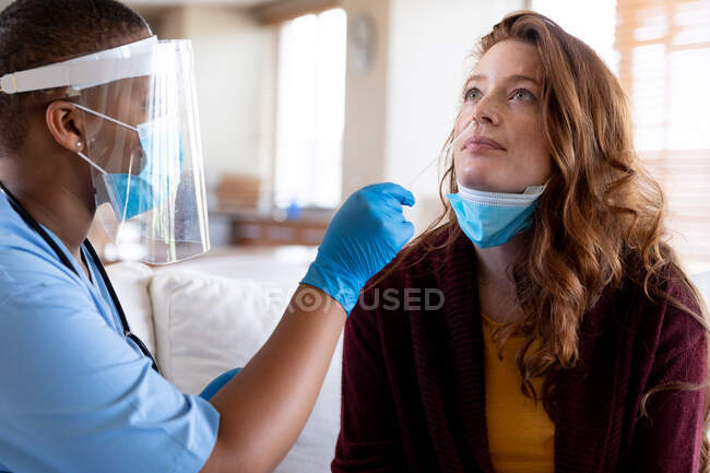 Жінка-лікар в захисній масці для обличчя приймає тест на мазок жінки в клініці під час епідемії ковадла-19. медичні послуги, профілактика хвороб та пандемія . — стокове фото