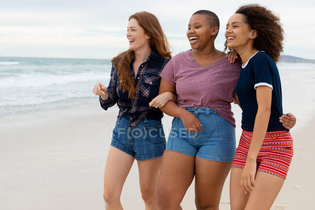 Alegre multirracial jovens amigas em casuals desfrutando fim de semana juntos na praia. amizade, socialização e lazer. — Fotografia de Stock