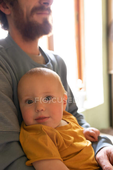 Porträt eines entzückenden süßen Babys, das auf einem jungen Vater zu Hause liegt. Familie und häuslicher Lebensstil. — Stockfoto