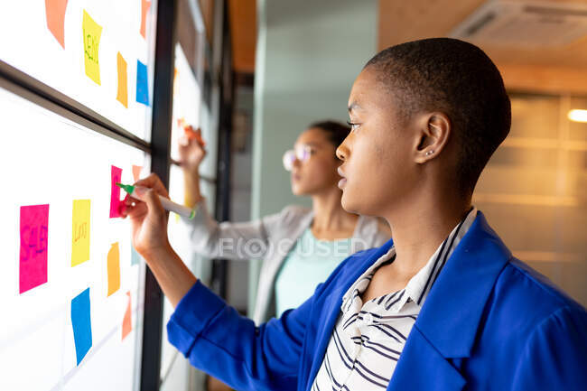 African american businesswoman planning strategy over sticky notes in creative office. entreprise créative, bureau moderne et plan d'affaires. — Photo de stock